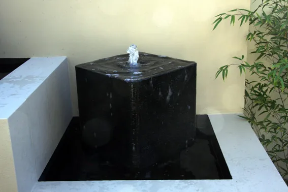 Black stone cube fountain in a courtyard water basin